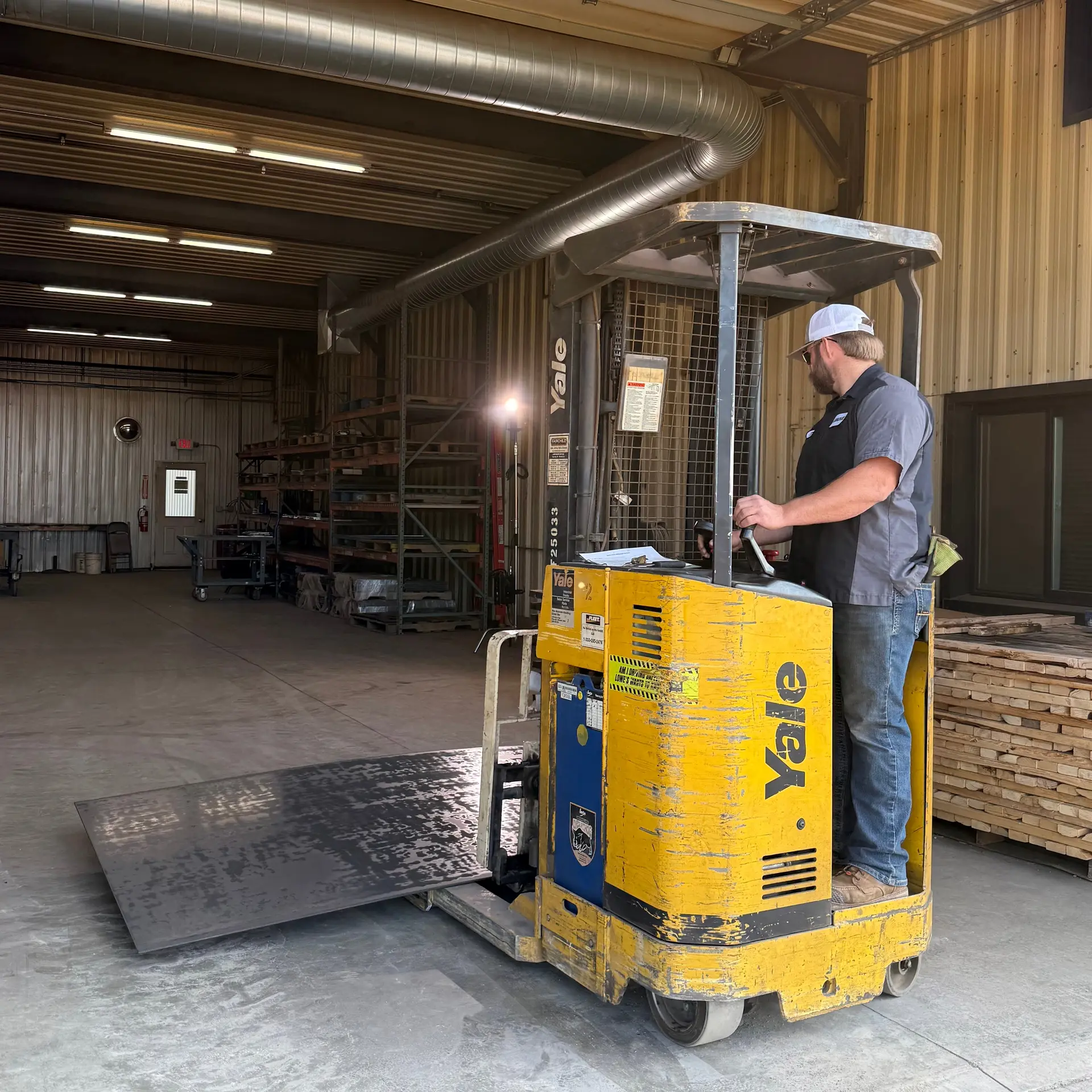 Worker operating a forklift with steel sheet in the MOVE Bumpers manufacturing facility